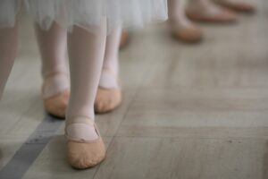 Feet of ballerinas lined up in ballet slippers and pink tights